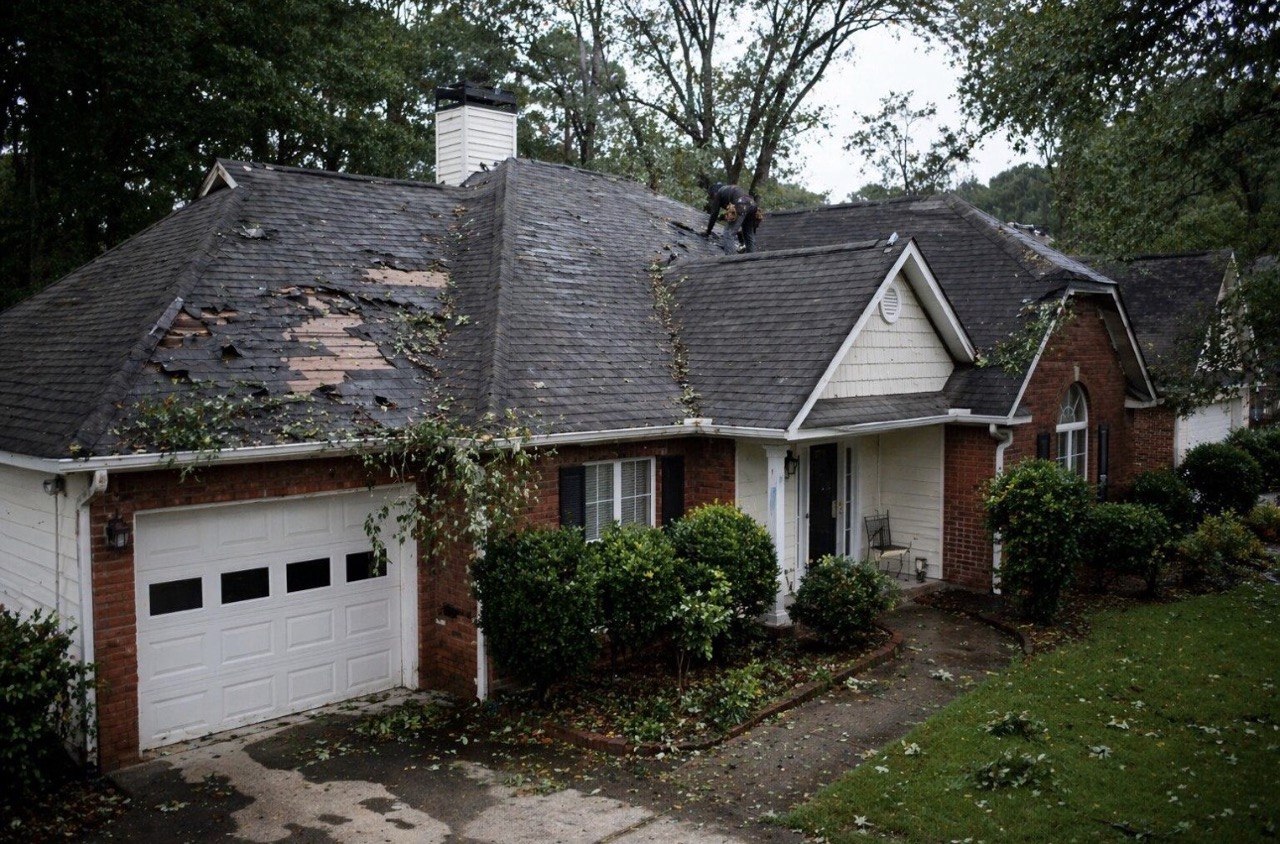 Storm damaged roof with missing shingles on Atlanta home
