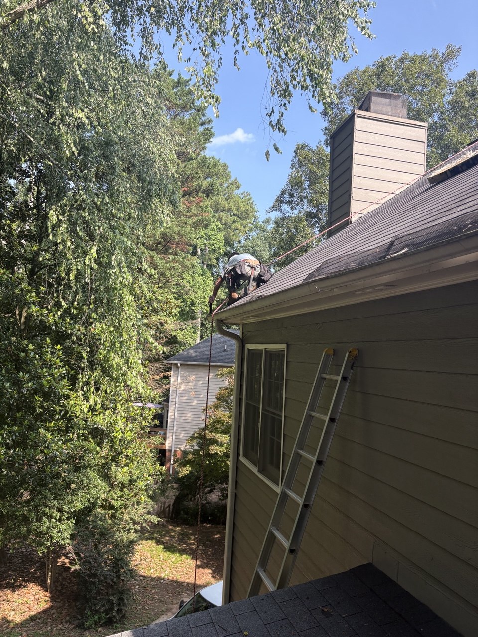 Roofer safely harnessed making chimney flashing repair