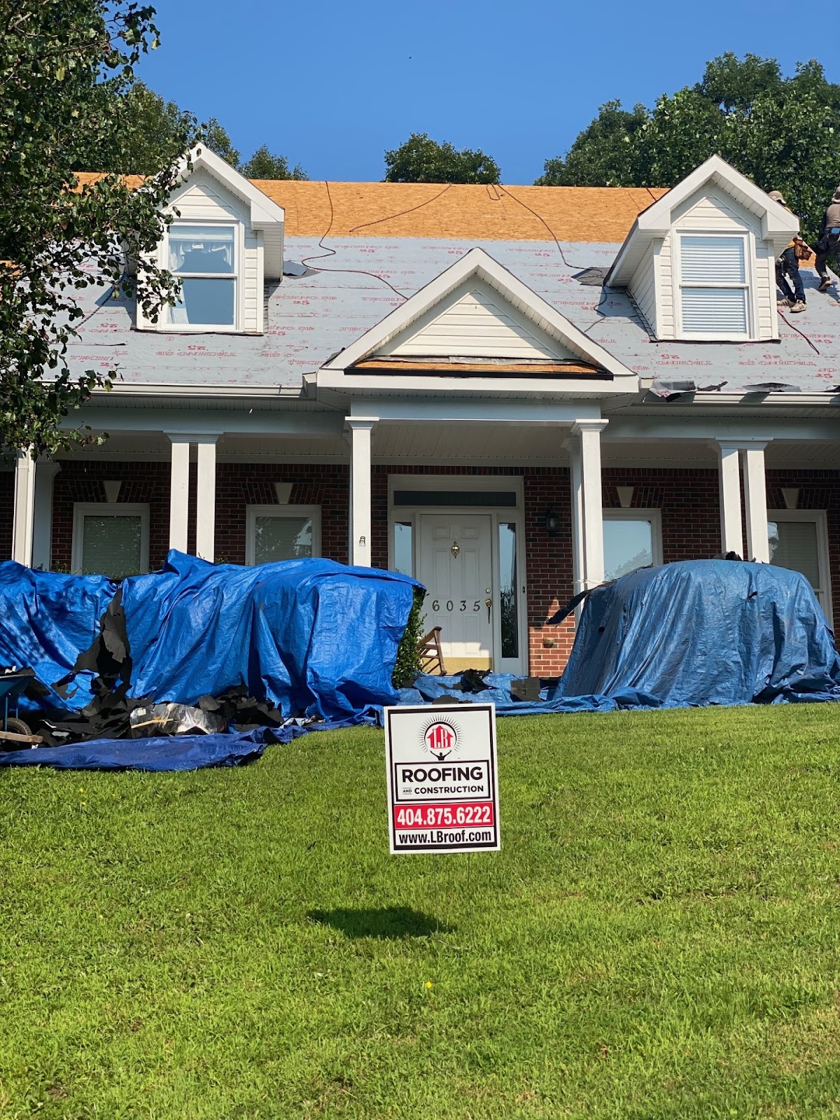 Roof replacement in progress. Synthetic felt underlayment going on, landscaping covered, 2026.
