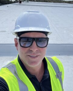 Charles (Lee) Marcum, owner of LB Roofing and Construction, on a job wearing a hard hat and safety vest